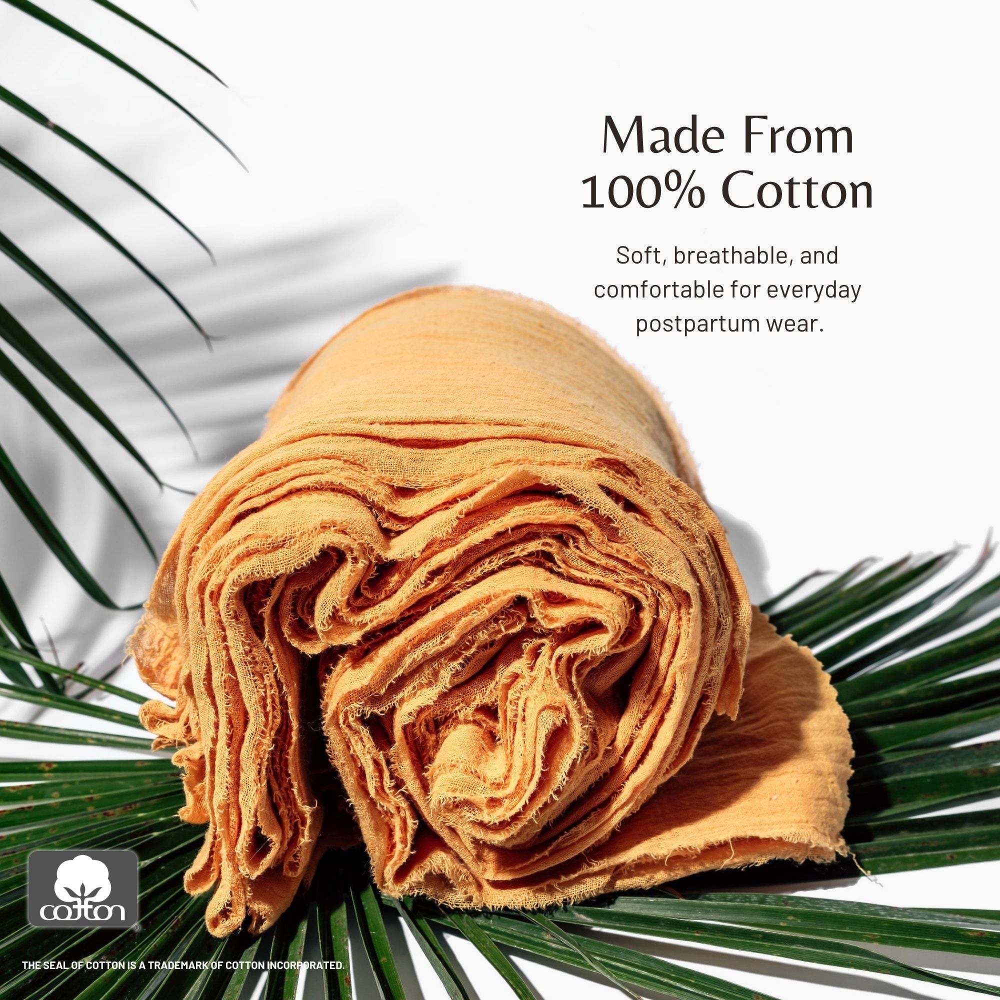 Rolled mustard yellow BelliBind postpartum wrap resting on palm leaves, featuring the Cotton Incorporated seal and text emphasizing it is made from soft, breathable 100% cotton for everyday wear.