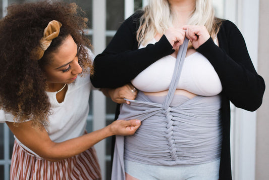Princess, a certified postpartum doula, wrapping a new mother in a Bellibind Bengkung belly wrap