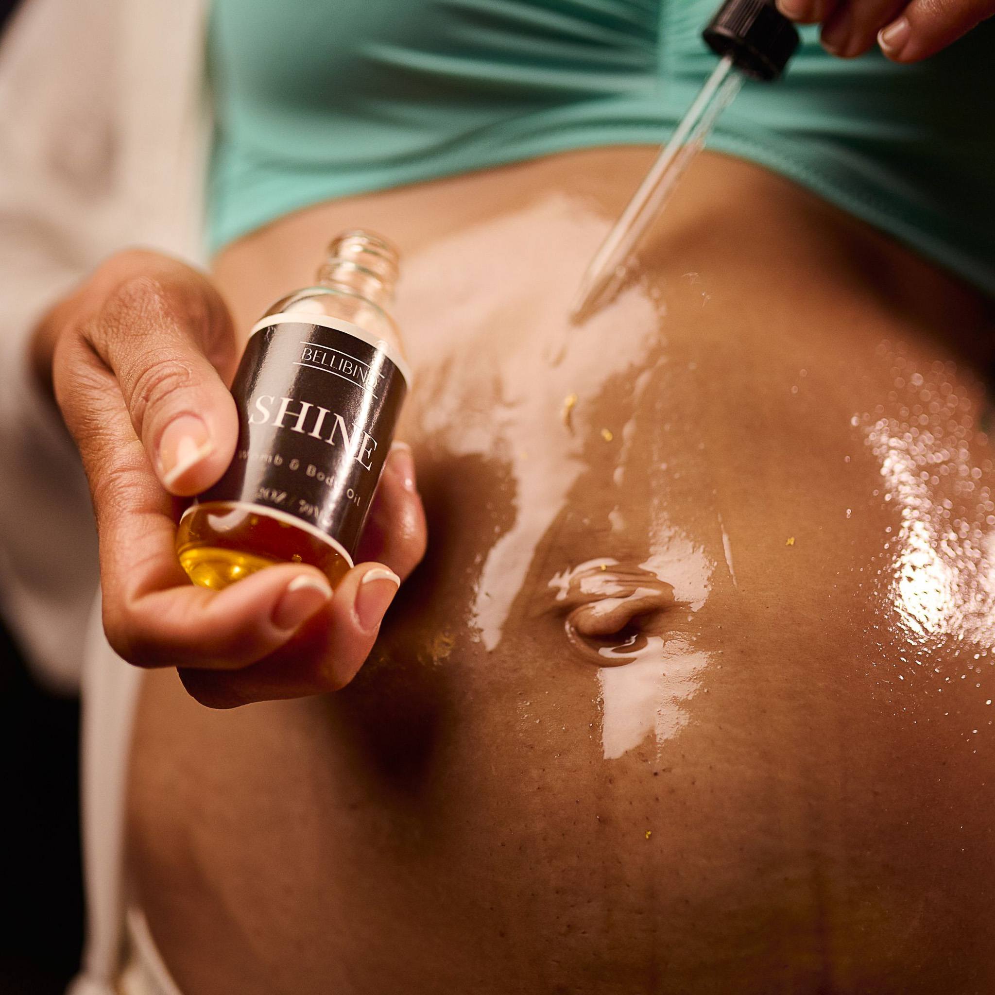 Bellibind Shine Belli and Body Oil applied to a bare postpartum belly with a glass dropper.